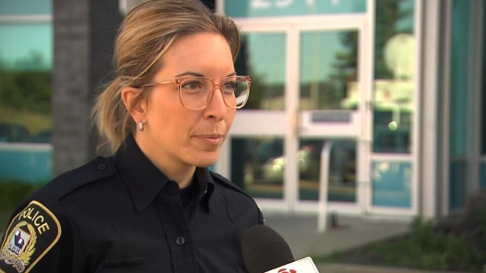 Julie Marois, porte-parole du Service de police de la Ville de Laval, parle aux médias devant un édifice.