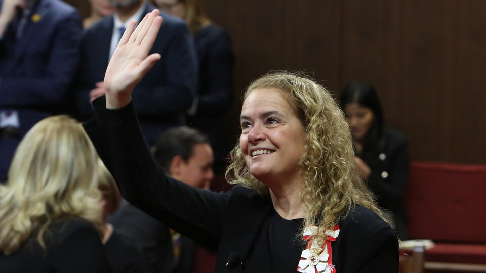 Mme Payette salue quelqu'un au loin en souriant.