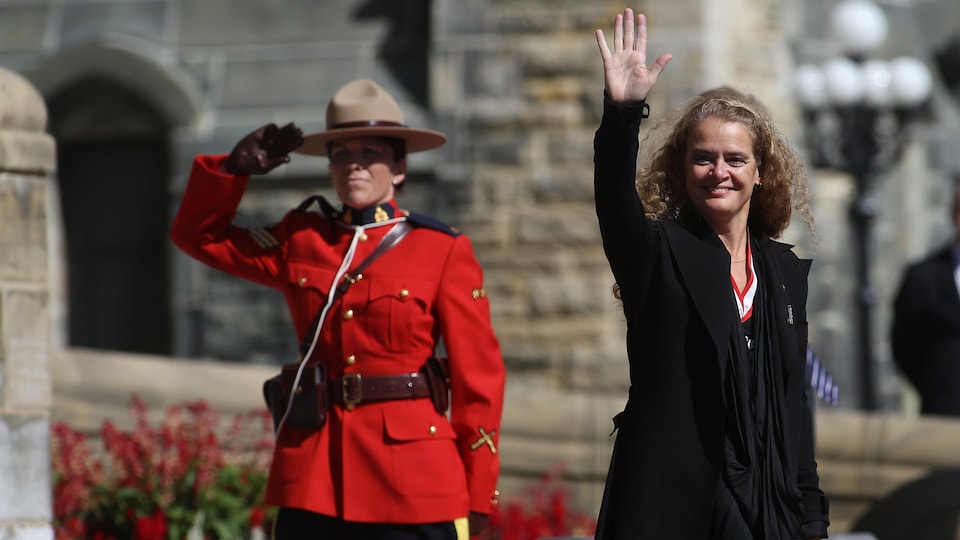 Julie Payette fait un salut de la main en passant devant une agente de la GRC.