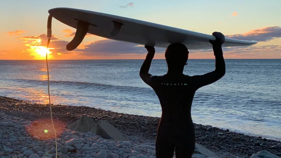 La jeune surfeuse transporte sa planche vers l'océan.