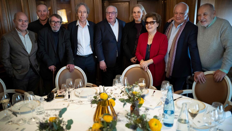 Les neuf personnes sont debout derrière une table et posent pour la photo.