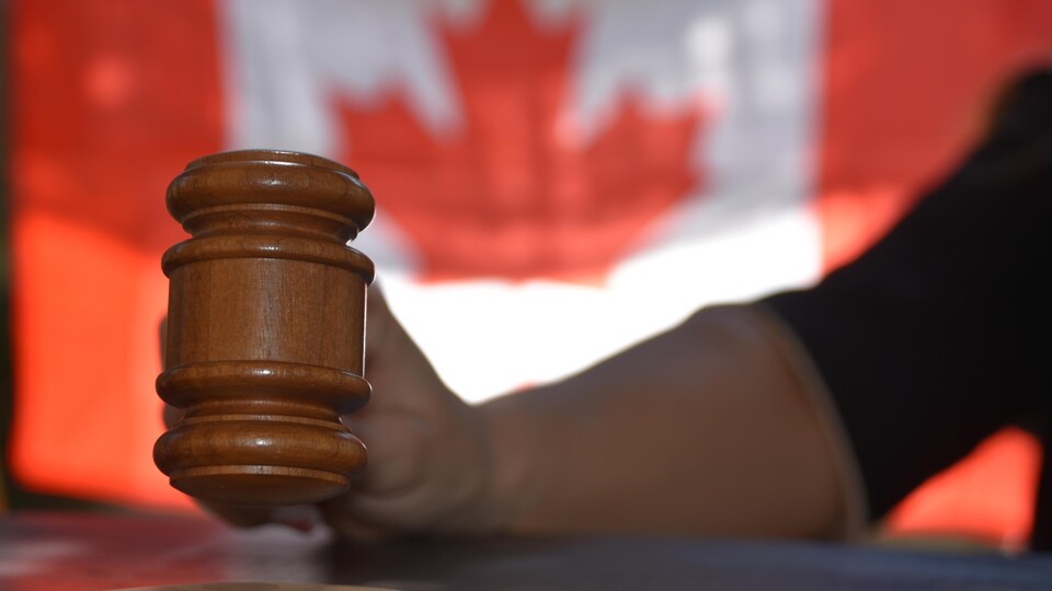 Gros plan sur le maillet d'une juge et drapeau du Canada en arrière-plan.
