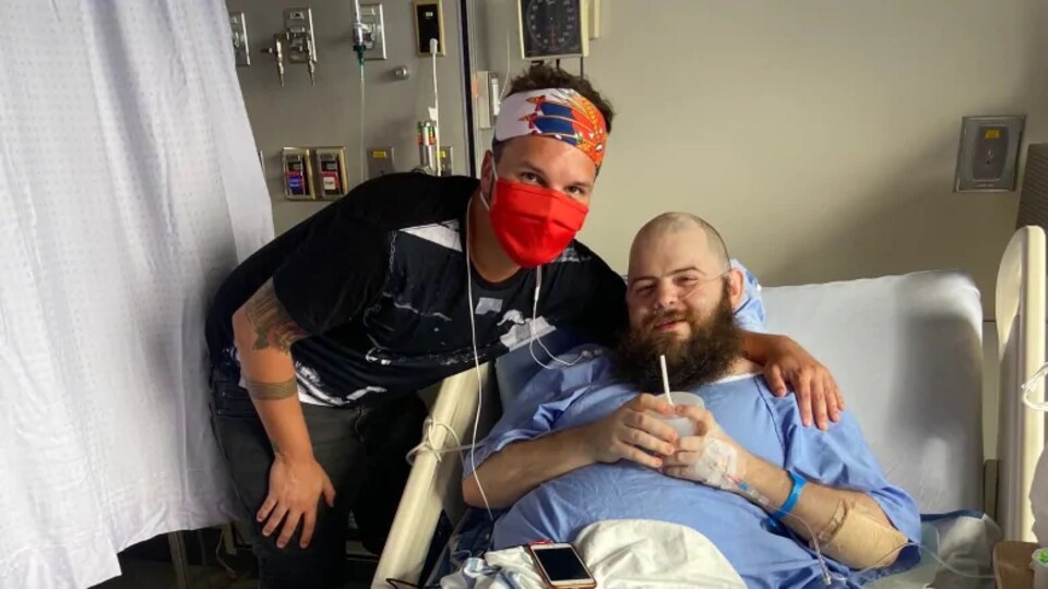 J.D. Burke et Justin Morissette posent pour la caméra alors que M. Morissette est allongé sur un lit d'hôpital.