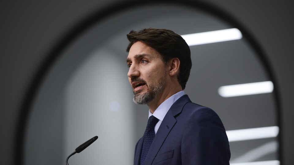 Plan moyen de Justin Trudeau devant un micro.