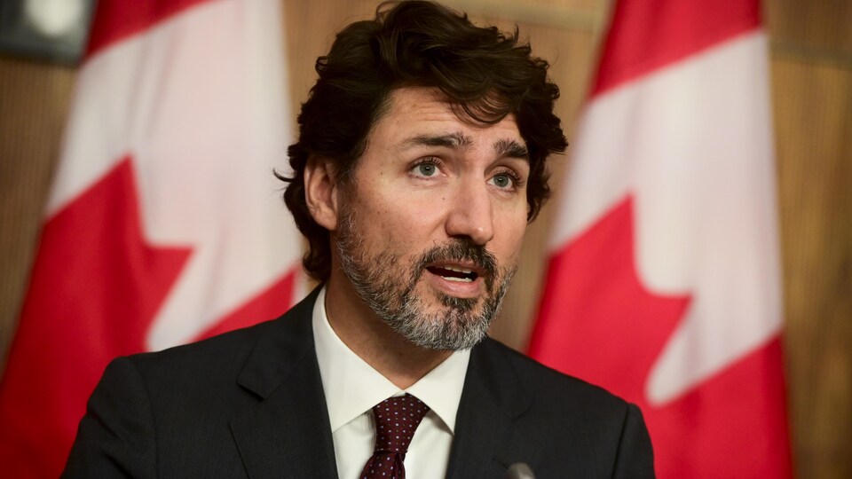 Justin Trudeau, devant des drapeaux canadiens. 