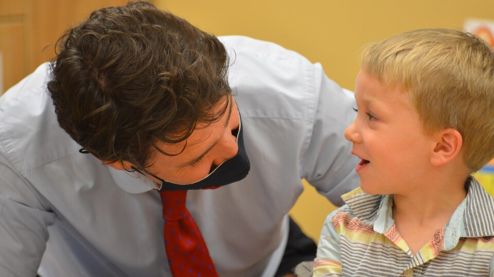 Justin Trudeau joue avec un jeune enfant dans une garderie. 