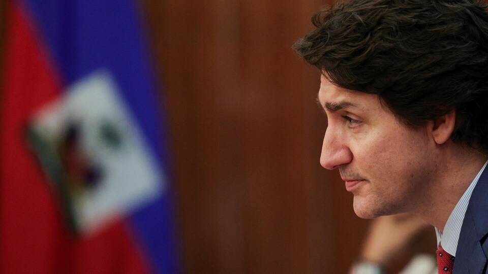 Justin Trudeau in front of the Haitian flag.