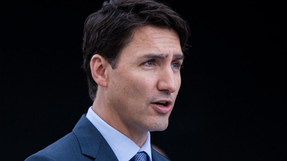 Portrait de Justin Trudeau qui parle devant un fond noir.