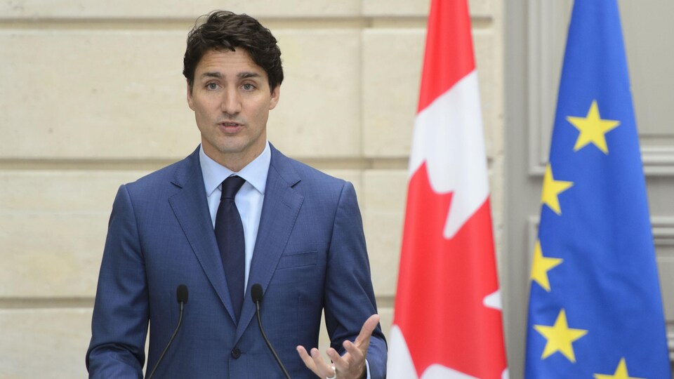 Justin Trudeau parle au micro devant un drapeau du Canada et de l'Union européenne.