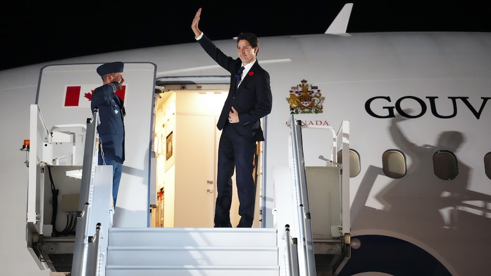 Justin Trudeau salue de la main avant de monter à bord d'un avion du gouvernement du Canada.