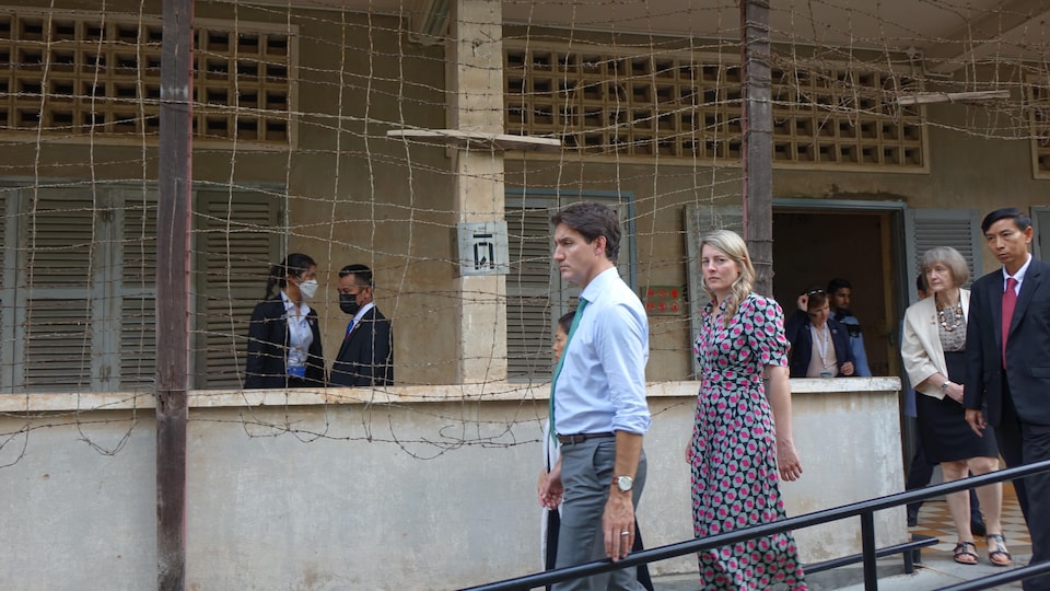 Justin Trudeau marche devant des fils barbelés sur les murs d'une ancienne prison des Khmers rouges.