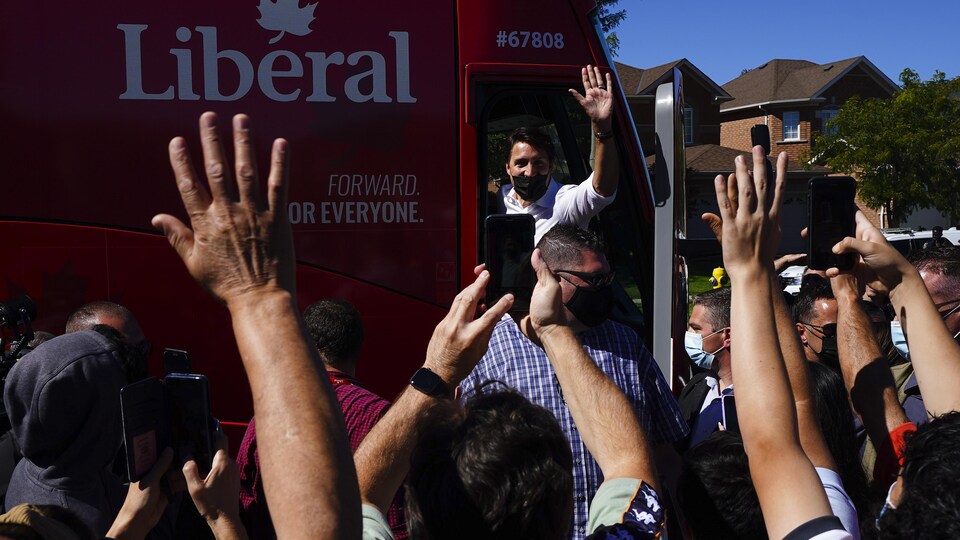 Justin Trudeau salue une foule de son autobus de campagne.