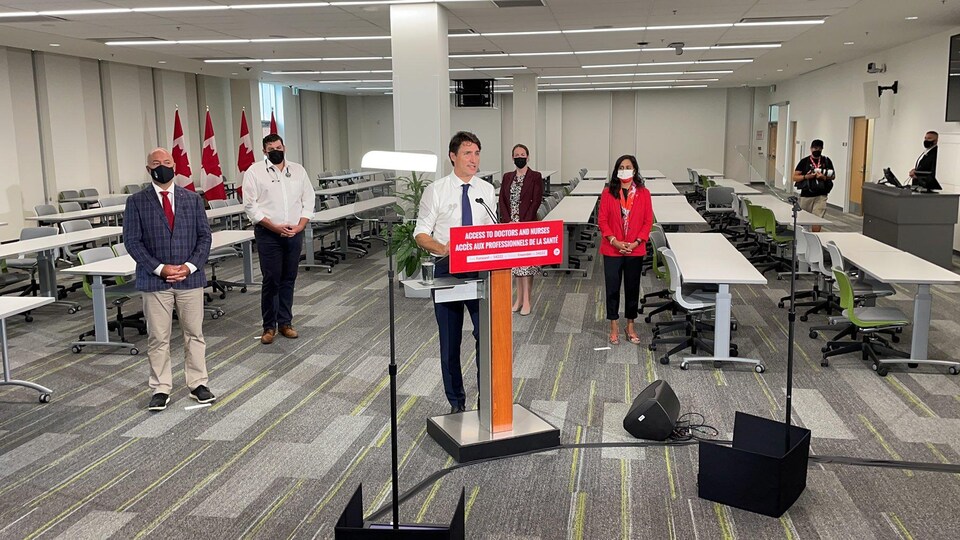 Justin trudeau en conférence de presse dans une salle universitaire.