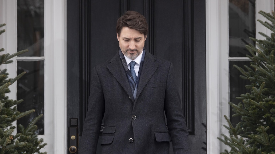 Justin Trudeau sort d'une maison.