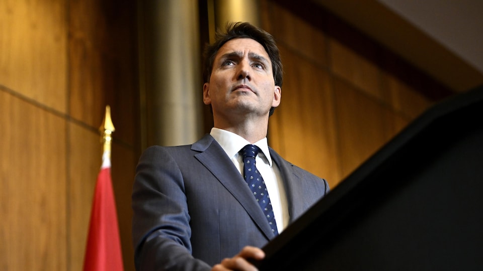 Justin Trudeau se tient debout derrière un lutrin. 
