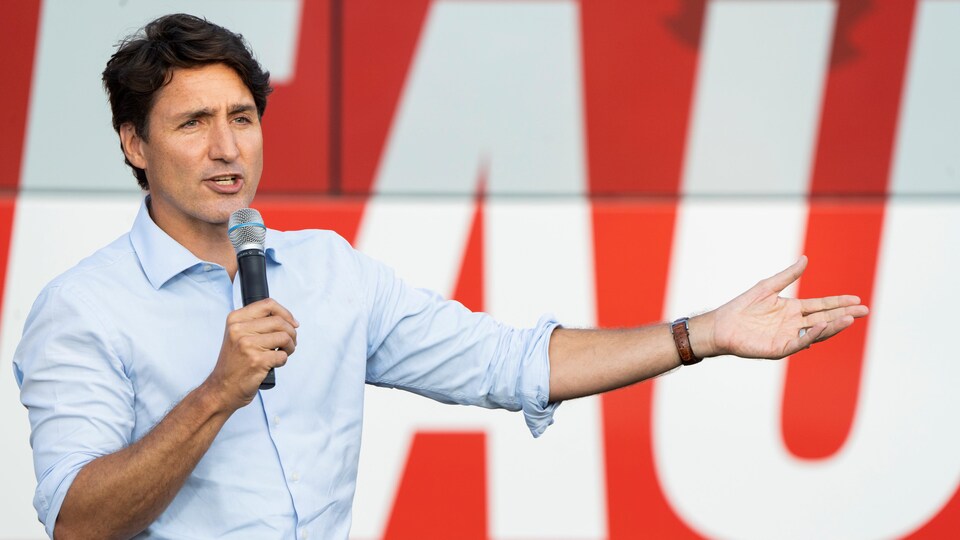 Justin Trudeau parle dans un micro et regarde au loin. 