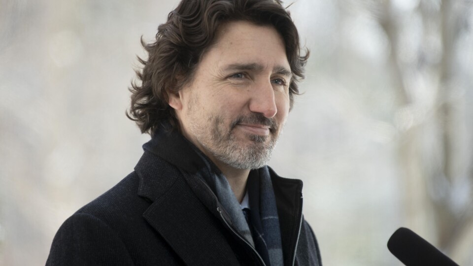 Justin Trudeau, dehors, derrière un micro durant un point de presse.