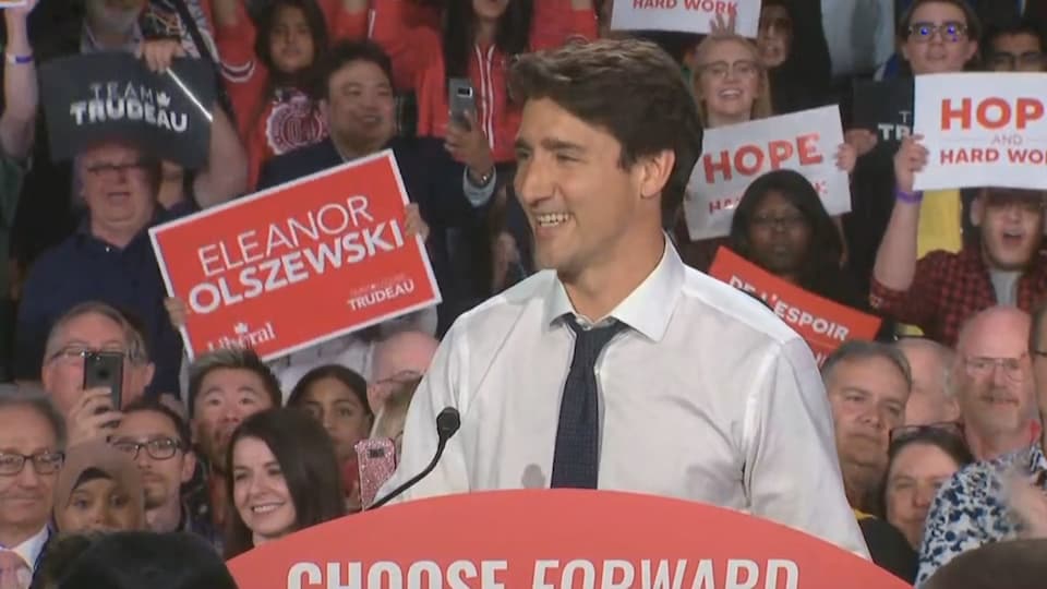 Justin Trudeau, tout sourire, sur une tribune devant ses partisans.