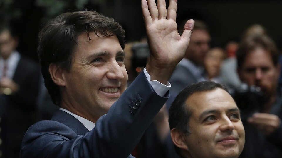 Justin Trudeau fait signe de la main avec un large sourire aux lèvres.