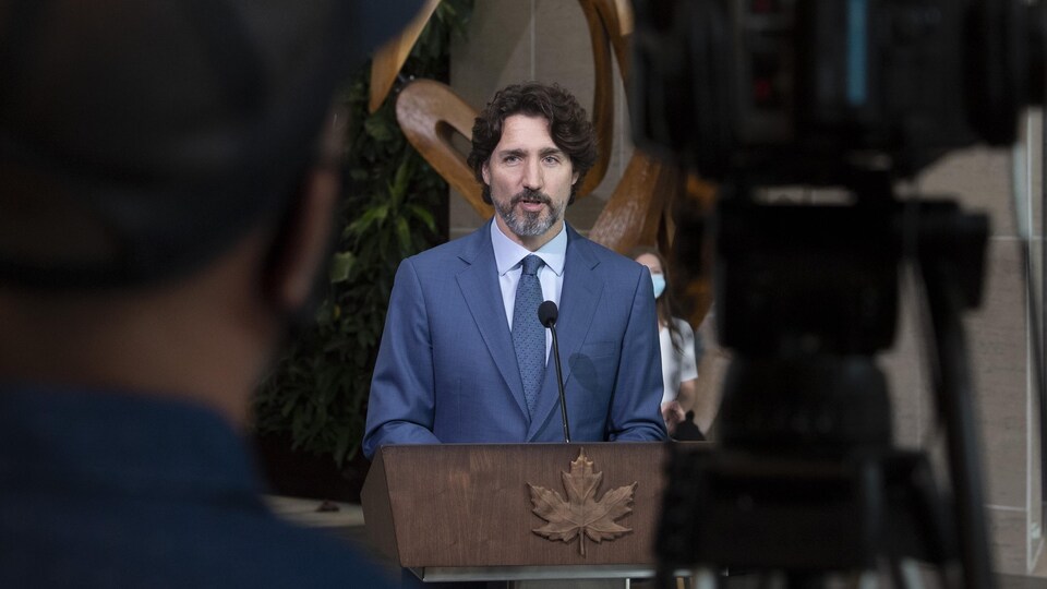 Le premier ministre Justin Trudeau debout derrière un lutrin et devant une caméra de télévision.