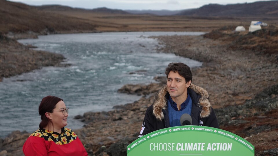 Justin Trudeau et Megan Pizzo-Lyall donnent une conférence de presse devant une rivière.