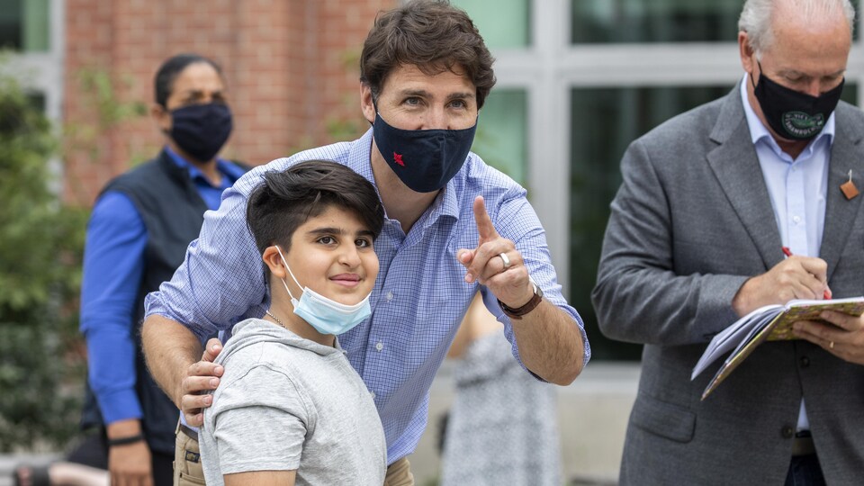 Justin Trudeau, en compagnie de John Horgan, parle à un garçon.