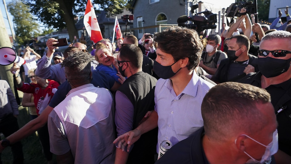 Justin Trudeau est entouré par des gardes du corps au milieu d'une foule.