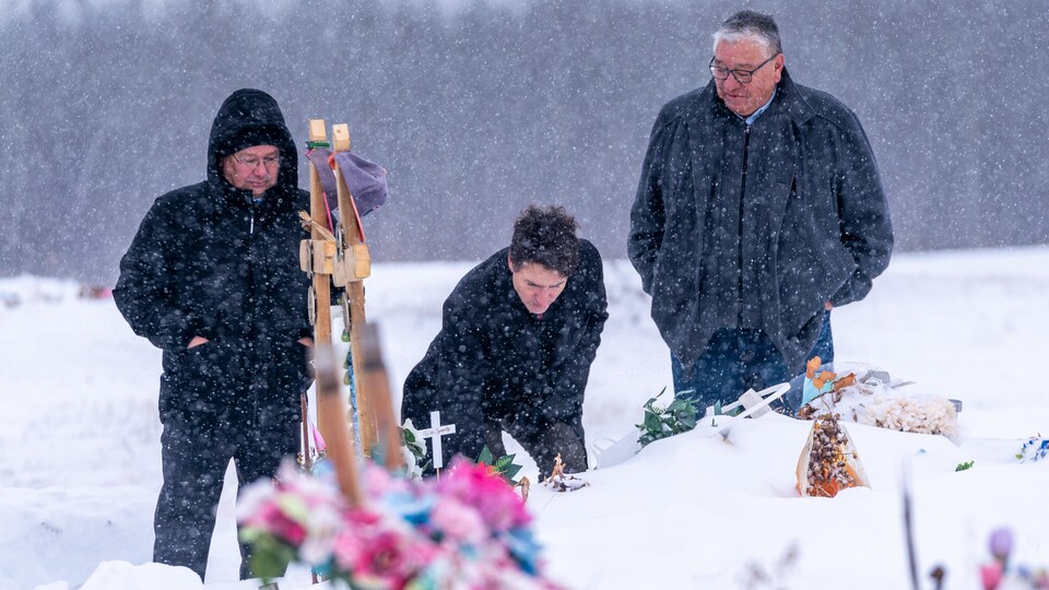Le premier ministre du Canada, Justin Trudeau, visite le cimetière de la Nation crie James Smith, en Saskatchewan, en compagnie du chef de la Première Nation, Wally Burns (à gauche), et du chef de Chakastaypasin, Calvin Sanderson (à droite), le 28 novembre 2022.