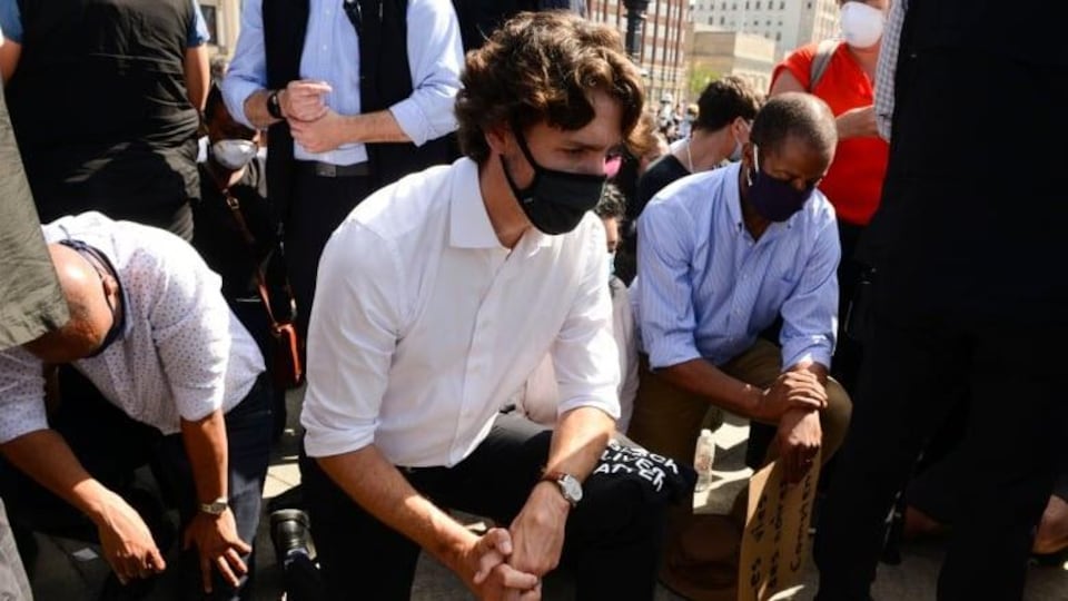 Justin Trudeau, un genou par terre, au milieu d'une foule.