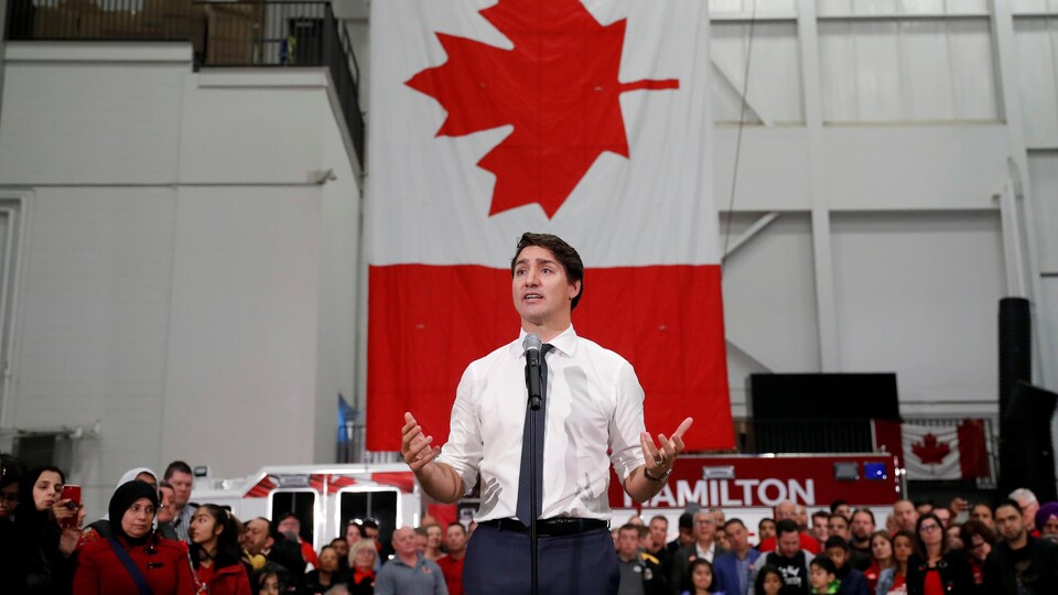 Justin Trudeau parle devant une foule dans une caserne de pompiers.