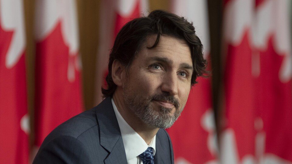 Justin Trudeau devant des drapeaux du Canada.