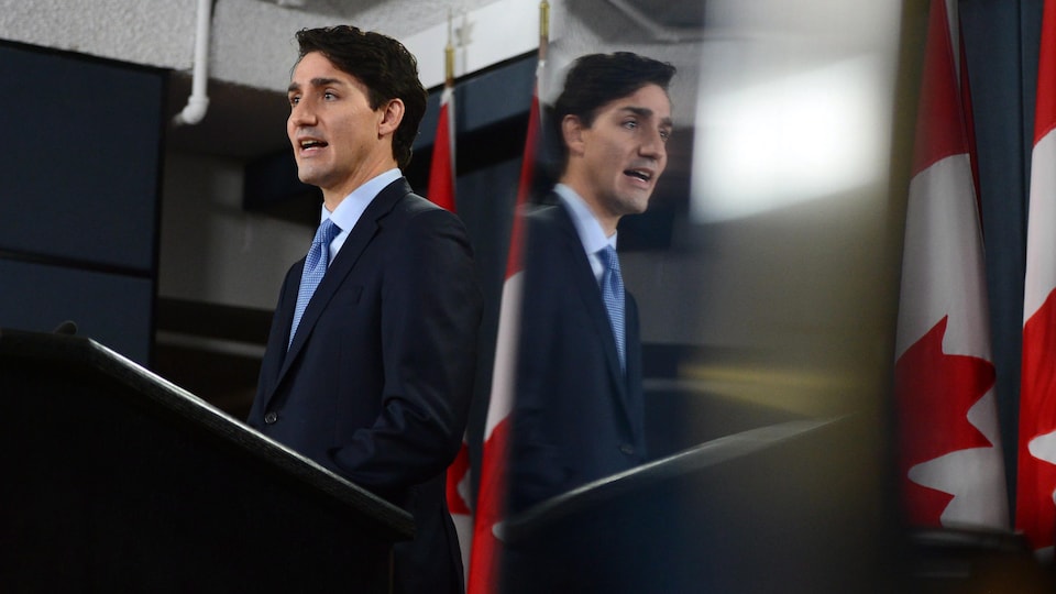 L'image du premier ministre Justin Trudeau se reflète dans un écran de télévision lors d'une conférence de presse donnée lundi midi.