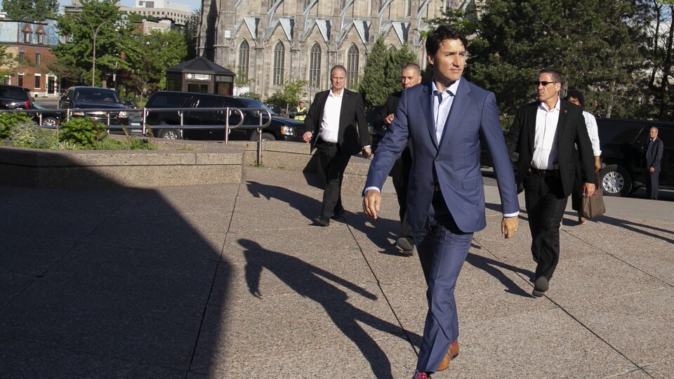 Justin Trudeau marche entouré de gardes de corps.