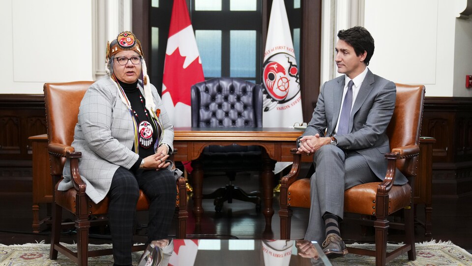Justin Trudeau et RoseAnne Archibald sont assis à une table sur la colline du Parlement à Ottawa.