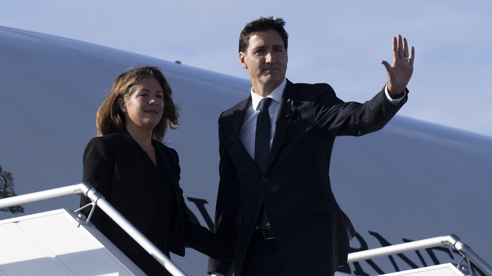 Justin Trudeau salue de la main en compagnie de son épouse, Sophie Grégoire, alors qu'ils sont sur le point d'embarquer à bord d'un avion.