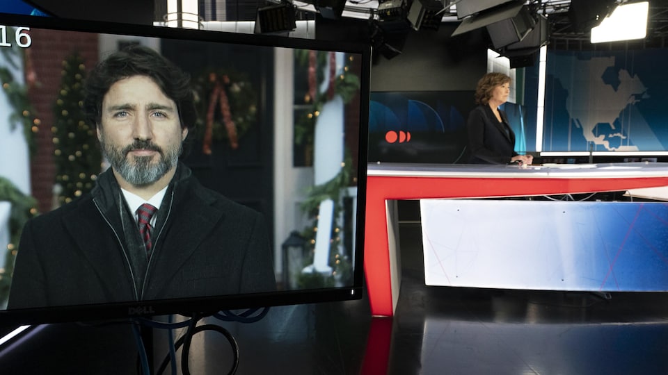 Céline Galipeau, sur le plateau du Téléjournal, en entrevue avec Justin Trudeau dont le visage apparaît sur un téléviseur.
