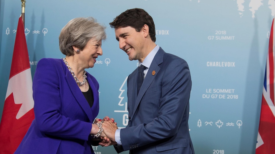 M. Trudeau et Mme May se serrent la main en souriant.