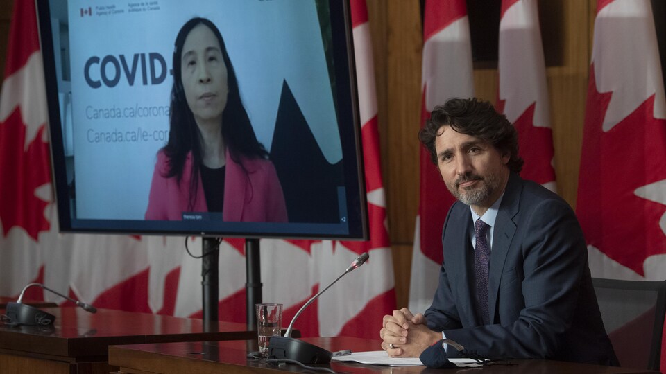 Le premier ministre Justin Trudeau et, sur un écran de télévision, l'administratrice en chef de la santé publique, la Dre Theresa Tam.