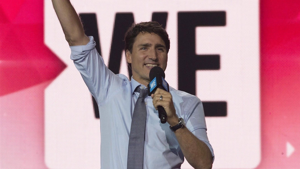 Justin Trudeau salue la foule sur une scène.
