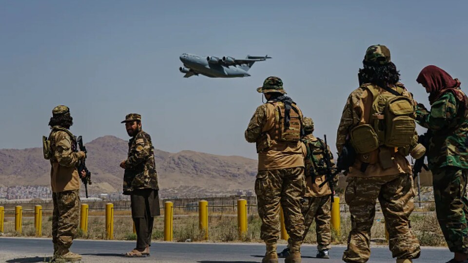 Un avion militaire décolle de Kaboul sous le regard de soldats occidentaux.