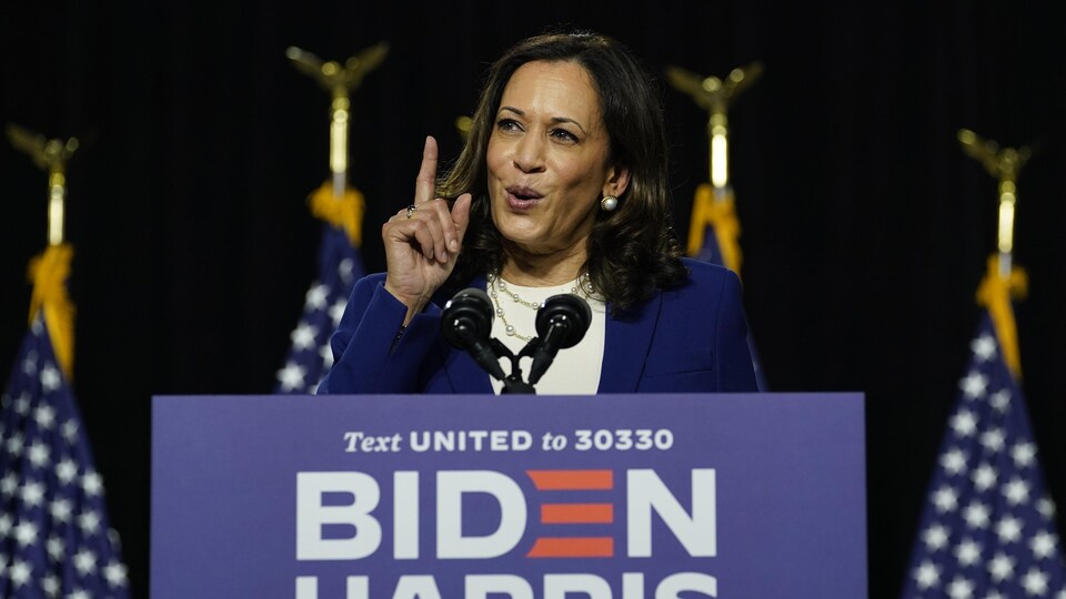 Kamala Harris parle sur une tribune l'index levé.