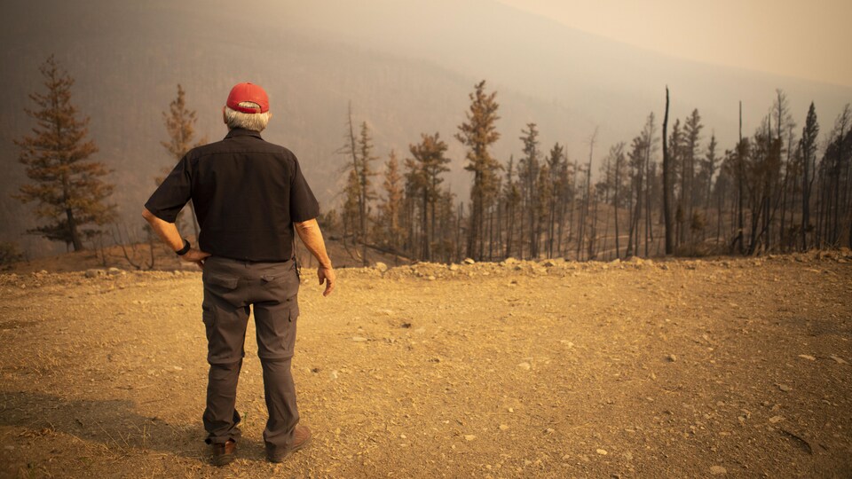 Ron Ignace devant une forêt brulée.