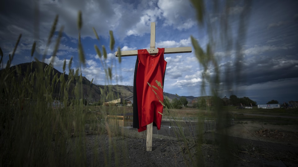 Une robe rouge sur une croix à Kamloops, en Colombie-Britannique suivant la découverte des tombes non marquées près de l'ancien pensionnat pour Autochtones.