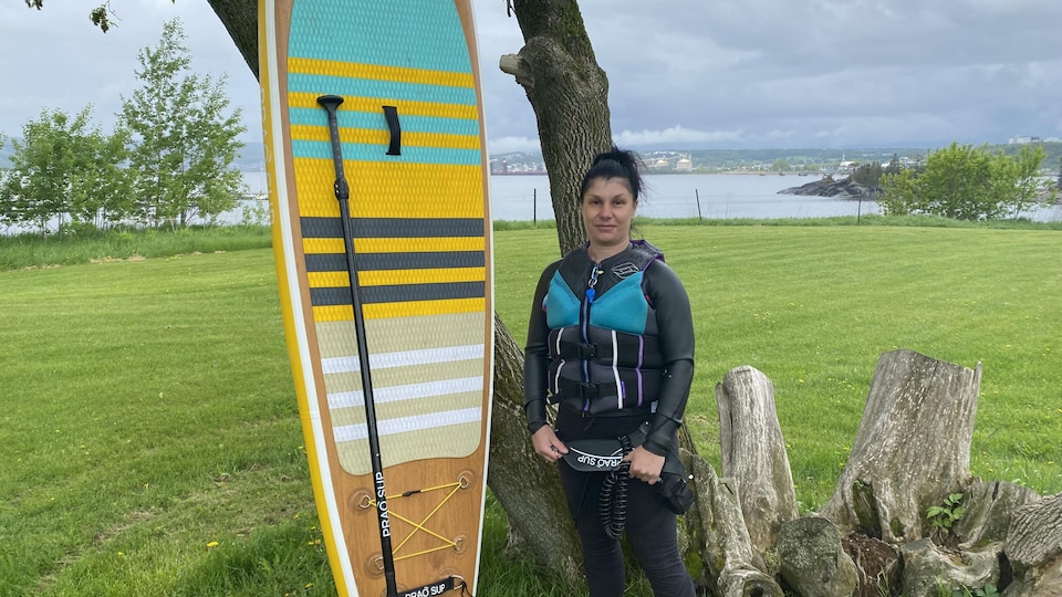 A woman next to her paddle board.