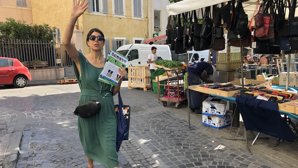 Elle interpelle un passant d'un signe de la main.