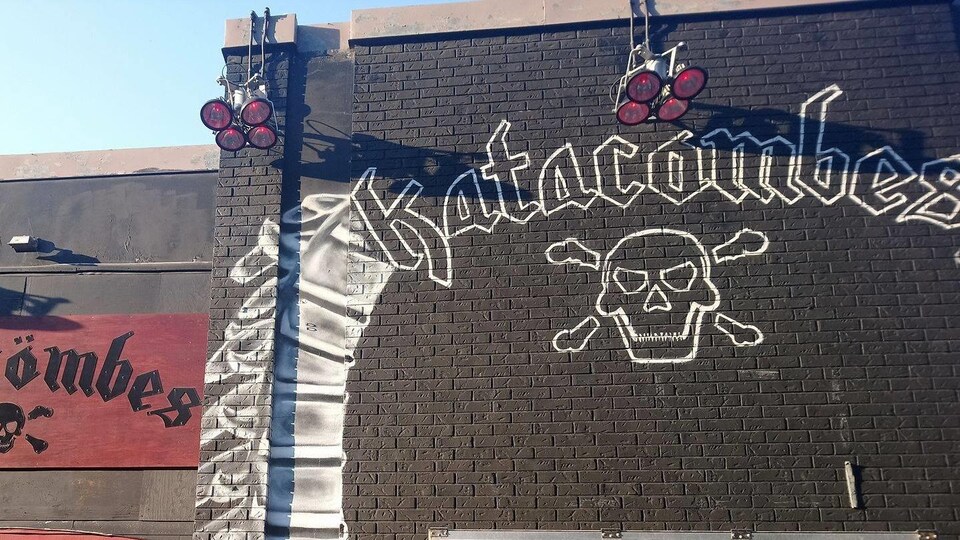 Image d'une façade des Katacombes, où l'on aperçoit le logo de la salle de spectacle peint sur un mur noir.