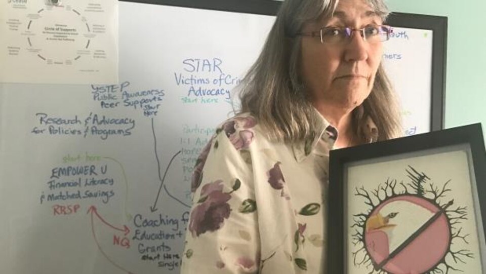 Kate Quinn s'occupe du CEASE, qui vient en aide aux femmes qui vivent dans la rue à Edmonton. Elle tient la peinture d'une de ses anciennes protégées, Gloria Neopetung, qui a perdu la vie.