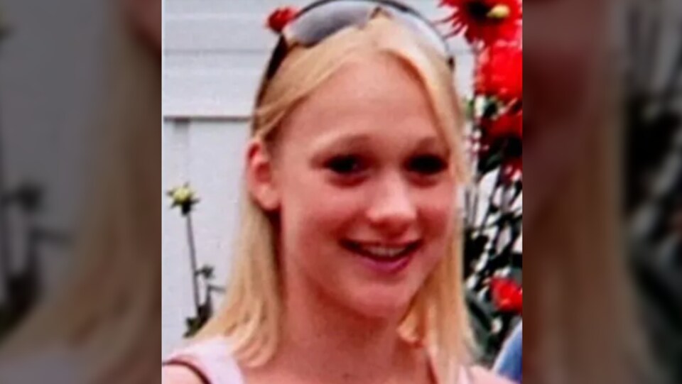 Une fille aux cheveux blonds avec des lunettes sur sa tête. Elle est sourante.