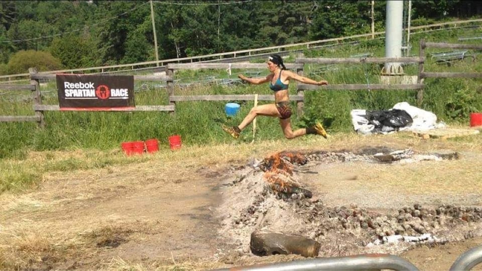 La femme participe à une course, la Spartan Race, sur un terrain accidenté.