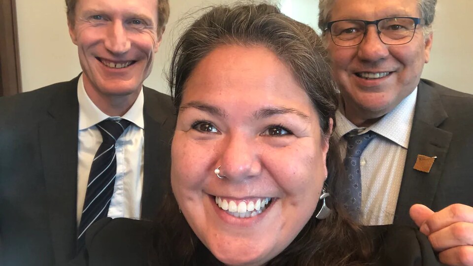 Kathy Kettler sourit avec à ses côtés Marc Miller et Dan Vandal, le ministre des Affaires du Nord.